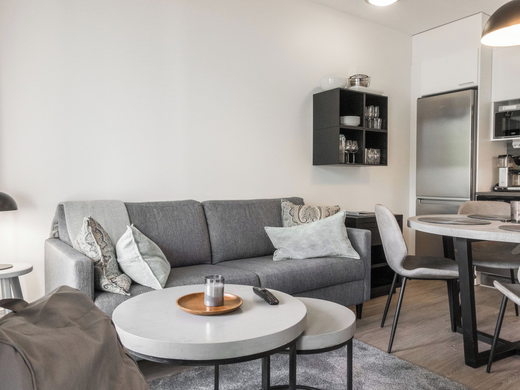 Un salon moderne avec un canapé gris, une table basse et un coin repas comprenant une petite table et des chaises.