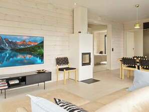 A modern living room with a flat-screen TV, a fireplace, and a dining area with chairs. - Villa horihane by Interhome (Inari)