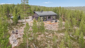 Une maison moderne entourée d’une forêt, sous un ciel dégagé.