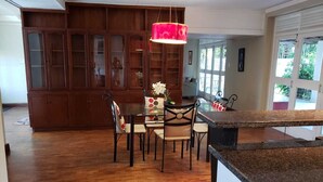 Una cocina amplia con armarios de madera, un comedor con mesa y sillas, y un ventanal que proporciona luz natural.