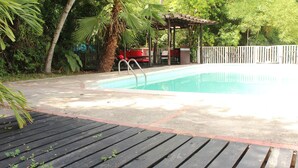 Una piscina con muelle de madera y zona de estar cubierta.