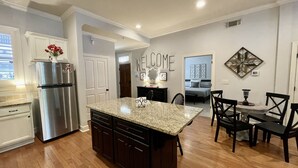 Una cocina moderna con una isla central, muebles oscuros y un refrigerador de acero inoxidable.