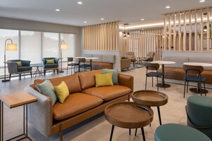 A modern lounge area with a brown leather sofa, round tables, and chairs.