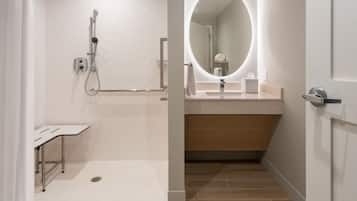 A modern bathroom with a shower, a vanity with a mirror, and a toilet.