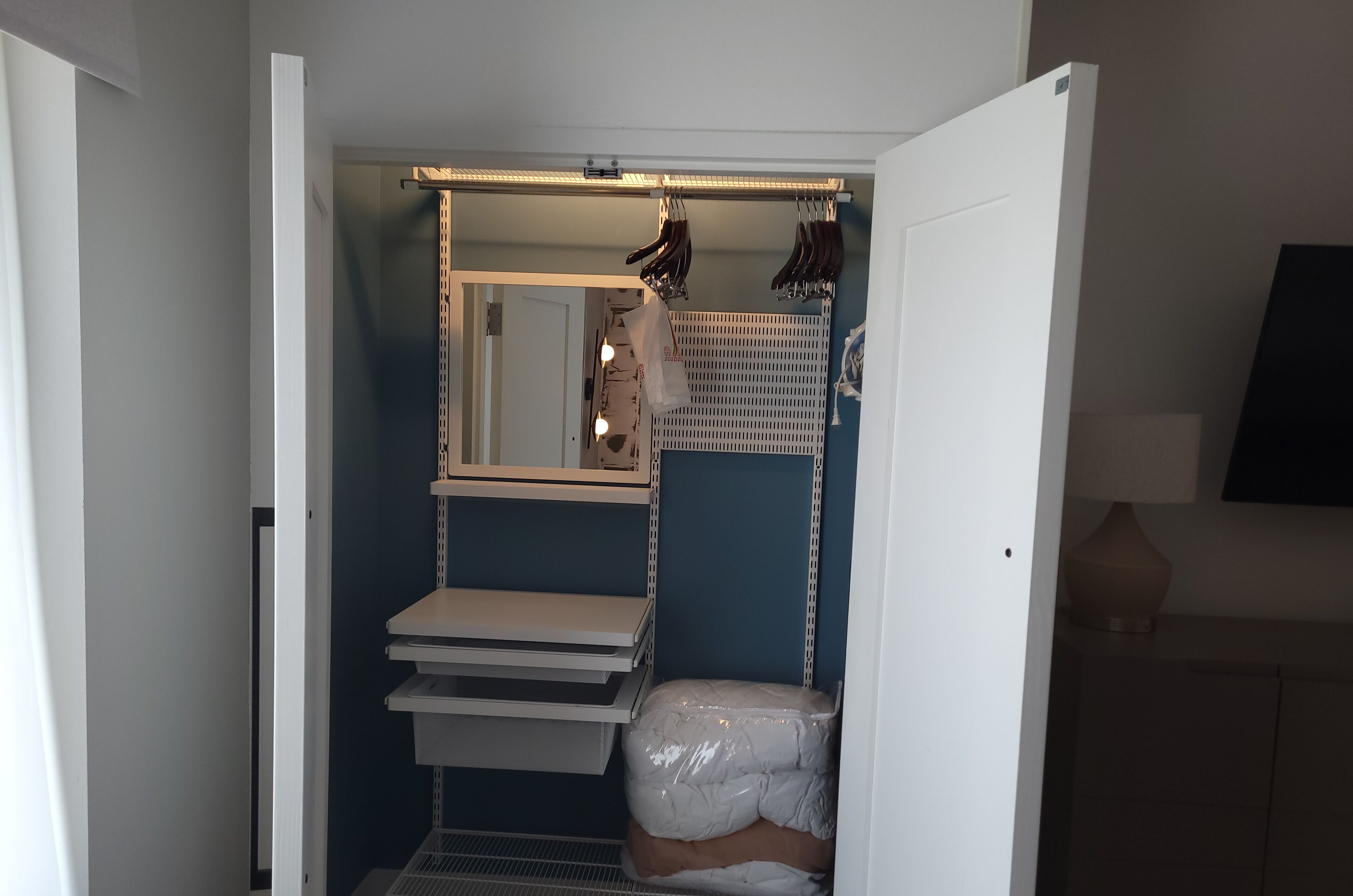 A compact bathroom with a mirror, shelves, and a towel rack.