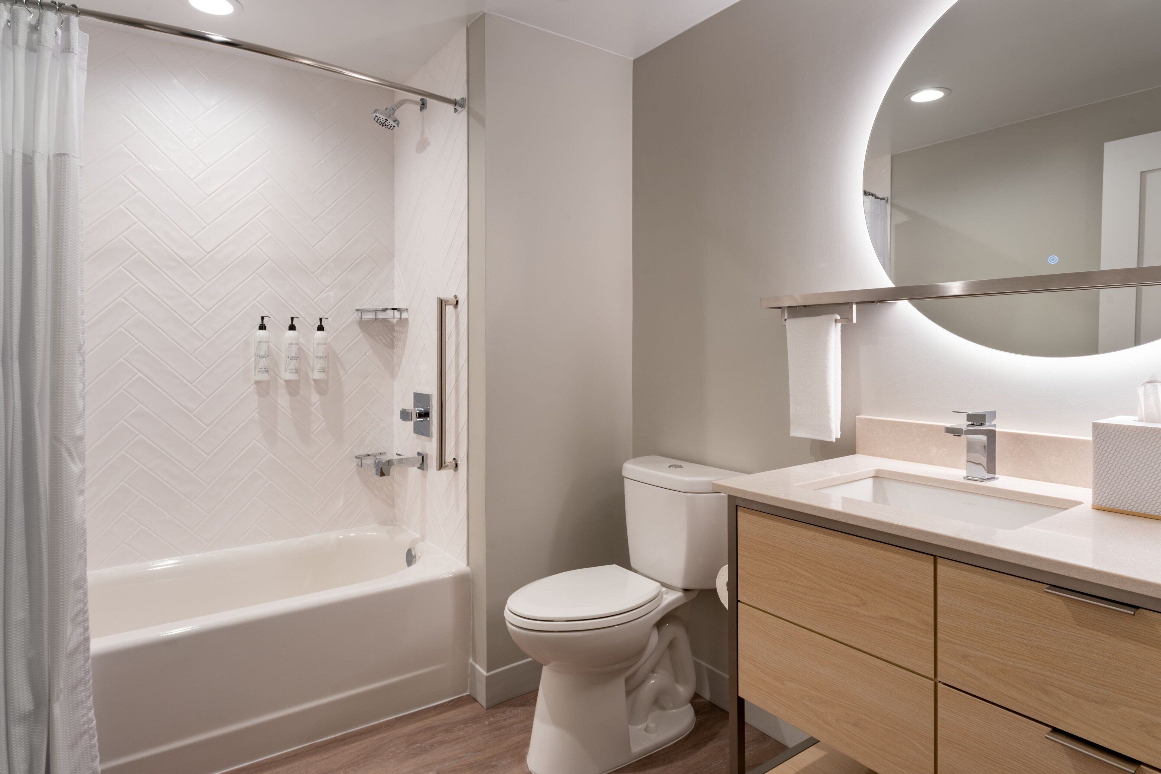 Une salle de bain moderne équipée d’une baignoire, de toilettes et d’un meuble-lavabo.