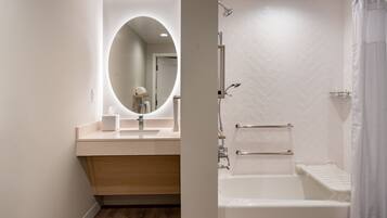 A modern bathroom with a round mirror, a sink, a bathtub, and a shower area.