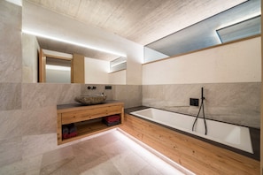 Une salle de bain moderne avec un meuble-lavabo en bois, un grand miroir et une baignoire sur pieds.