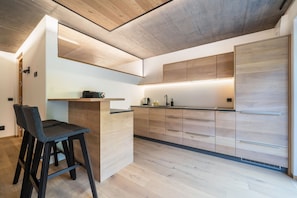 Une cuisine moderne avec des meubles en bois, un comptoir-bar et un tabouret de bar.