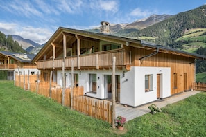 Un chalet en bois doté d’un balcon, de murs blancs et d’une terrasse en bois.