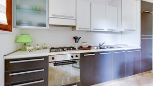 A modern kitchen with white cabinets, a stainless steel stove, and a built-in oven. - Vacation Home "Antonella Sul Golf" with Shared Pool, Private Terrace & Wi-Fi (Is Arenas)