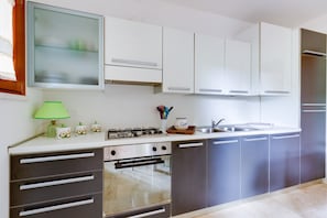 A modern kitchen with white cabinets, a stainless steel stove, and a built-in oven.