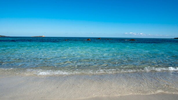 A beach with clear water, sandy shore, and distant land. - Vacation Home "Antonella Sul Golf" with Shared Pool, Private Terrace & Wi-Fi (Is Arenas)