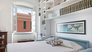 Une chambre à coucher avec un lit, une fenêtre, une bibliothèque et un tableau encadré au mur.