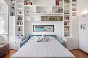 A bedroom with a bed, bedside tables, a bookshelf, and a framed picture on the wall. - Apartment close to the Sea with Sea View & Wi-Fi (Chiavari)
