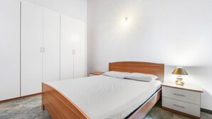 A bedroom with a wooden bed, white bedding, a bedside table with a lamp, and a wardrobe. - Holiday Home Residence Sulcis 2 with Shared Terrace & A/C (Masainas)