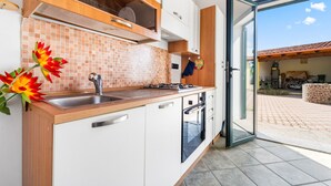 A modern kitchen with a sink, stove, and cabinets, leading to an open patio with a tiled roof. - Holiday Home Residence Sulcis 2 with Shared Terrace & A/C (Masainas)