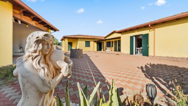 A statue in a courtyard with yellow buildings and a red brick pathway. - Holiday Home Residence Sulcis 2 with Shared Terrace & A/C (Masainas)