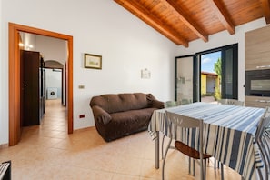 A dining area with a table and chairs, a sofa, a wooden ceiling, and a view through a glass door. - Holiday Home Residence Sulcis 7 with Shared Terrace & A/C (Masainas)