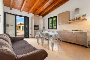 Cozinha moderna com área de jantar, vigas de madeira no teto e vista pela porta.