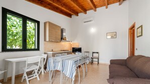 A dining area with a table and chairs, a kitchen in the background, and a brown sofa. - Holiday Home Residence Sulcis 7 with Shared Terrace & A/C (Masainas)