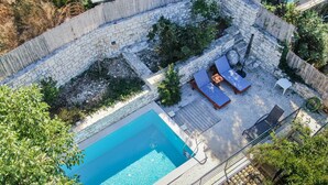 An aerial view of a backyard with a swimming pool, stone walls, and outdoor seating. - Villa Adamantia Paxos with Pool, Terrace & Wi-Fi (Paxos)