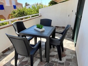 Un balcon avec une table et des chaises, un pot de fleurs et une vue sur des immeubles et de la verdure.