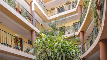 A multi-level atrium with balconies, columns, and potted plants.