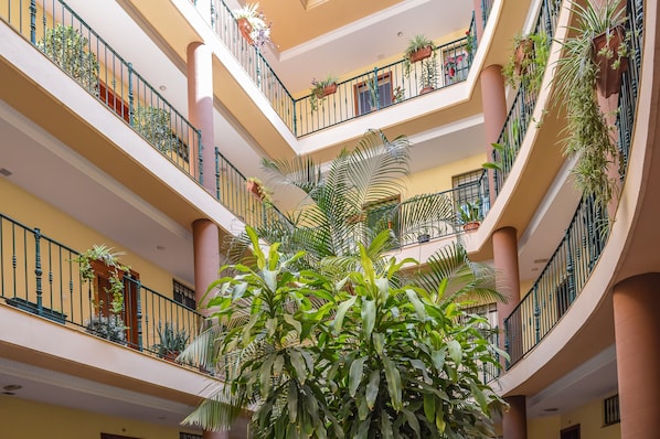 A multi-level atrium with balconies, columns, and potted plants.