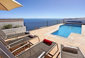 Ein Pool auf dem Dach mit Blick auf das Meer, Liegestühle und eine Pergola.