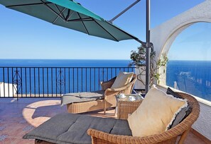 A balcony with wicker chairs, a table with cups, and a view of the sea. - Beautiful Villa with Sea Views, Pool, Garden & Wi-Fi (Salobreña)