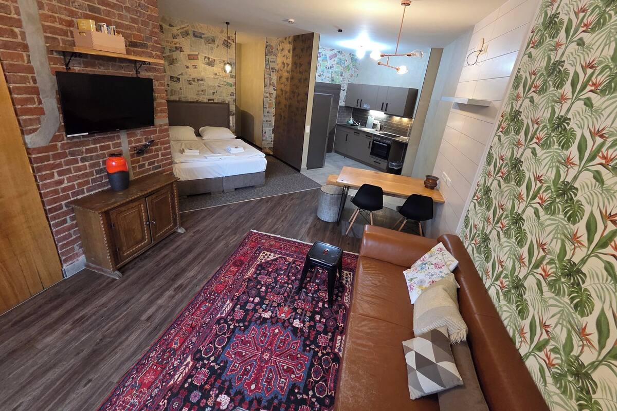 Un espacio habitable compacto con cama, sofá, comedor y kitchenette.
