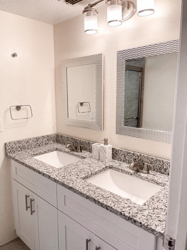 Un baño con dos lavamanos, un espejo y un dispensador de toallas.