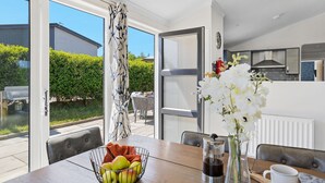 A modern kitchen with a built-in oven and a dining area with a table set for two. - Hazel Lodge, 27 Roadford Lake Lodges (Lifton)