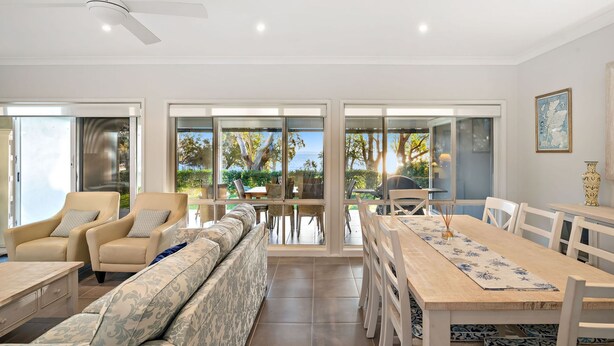 Un salón espacioso con un sofá grande, una mesa de comedor y vistas al exterior.