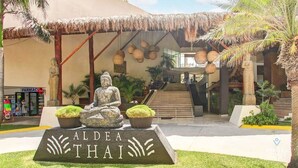 Una estatua de Buda frente a un edificio con un letrero que dice "ALDEA THAI".