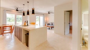Une cuisine moderne dotée d’un îlot central, de luminaires suspendus et d’un ventilateur de plafond.