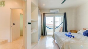 Une chambre d’hôtel avec un lit, un ventilateur de plafond, un appareil de climatisation, un hamac et une vue sur l’extérieur.