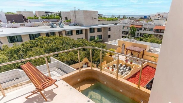 Un espace piscine aménagé sur le toit, comprenant deux chaises longues en bois, une petite table et un jacuzzi.