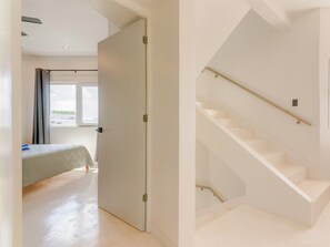 A modern hotel room with a bed, a door, and a staircase.