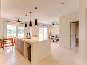 Une cuisine moderne dotée d’un îlot central, de luminaires suspendus et d’un ventilateur de plafond.