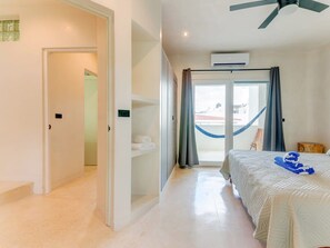A hotel room with a bed, a ceiling fan, an air conditioning unit, a hammock, and a view of the outside. - 5th Ave Rooftop Pool with Ocean Views and BBQ (Playa del Carmen)