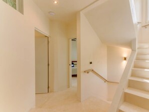 A staircase with a handrail leading to a landing, a door at the bottom, and a light fixture above the stairs. - 5th Ave Rooftop Pool with Ocean Views and BBQ (Playa del Carmen)
