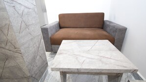 A modern room with a marble-patterned wall, a grey sofa, and a marble-topped table. - Hotel A1 Vastrapur (Ahmedabad)