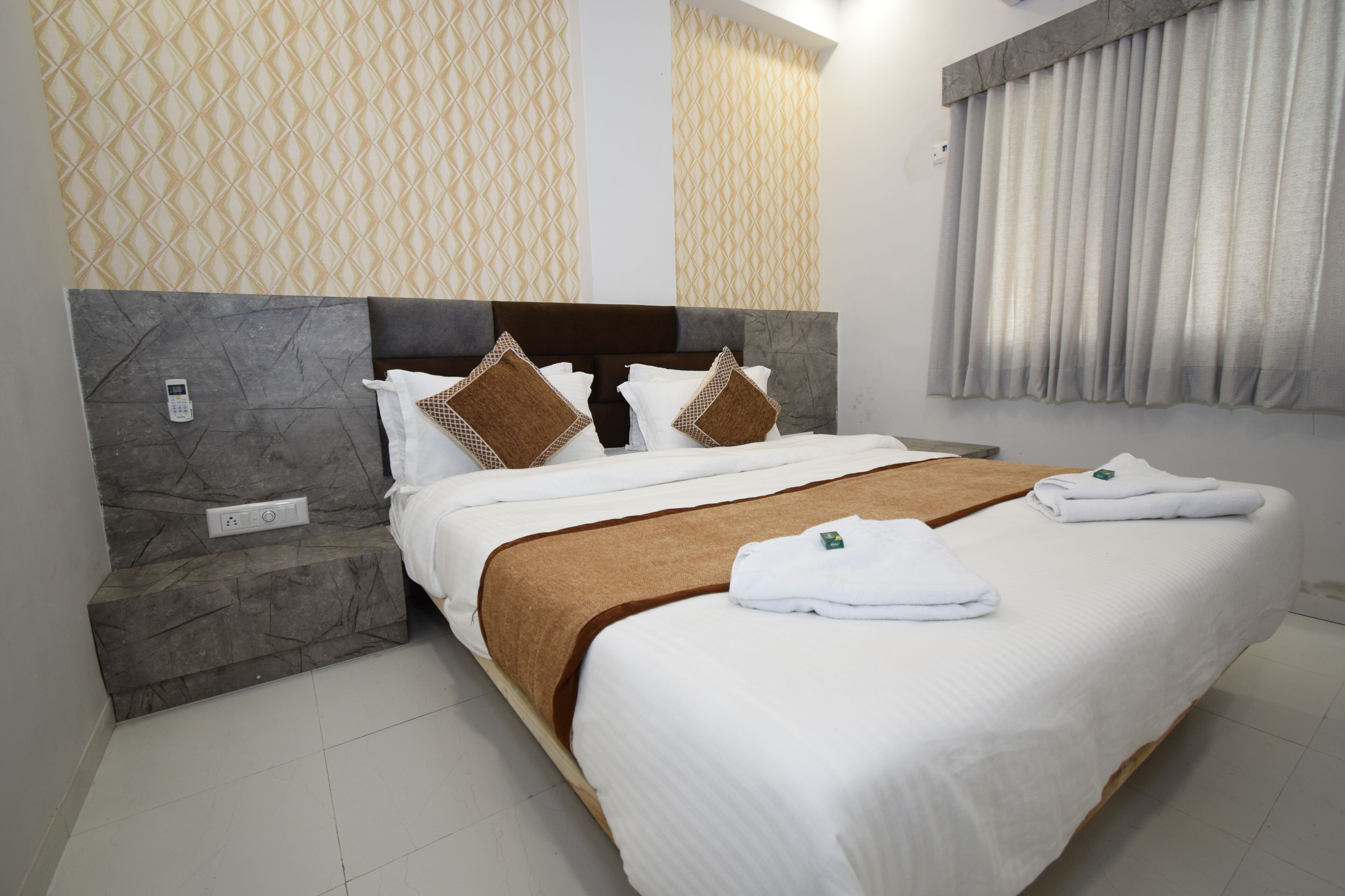 A neatly made bed with a brown accent, white pillows, and a folded towel on the bed.