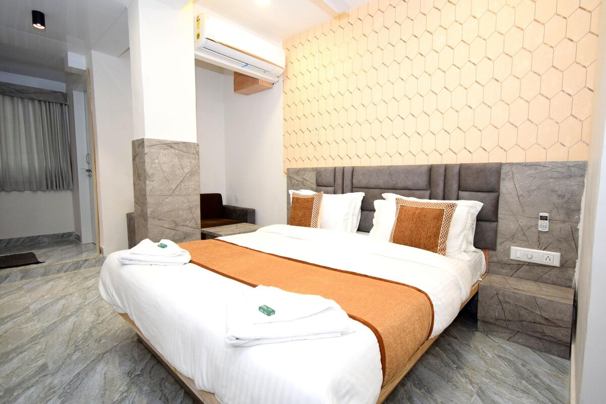 A hotel room with a bed, a desk, an air conditioning unit, and a wall with a honeycomb pattern.
