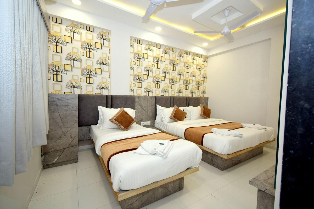 A hotel room with two beds, marble headboards, patterned wall decor, and a ceiling fan.
