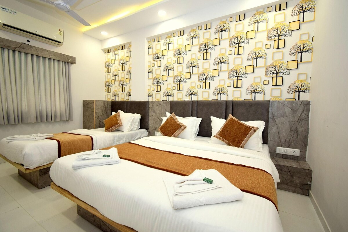 A hotel room with two beds, a marble headboard, a wall with a tree pattern, and an air conditioning unit.