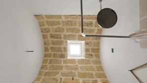 Ein Zimmer mit Steinwand, kleinem Fenster und einer Metallstange.