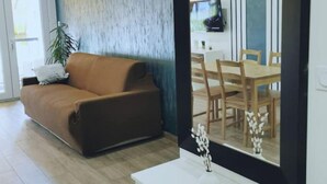 En moderne stue med en brun sofa, et hvidt konsolbord og et stort spejl.